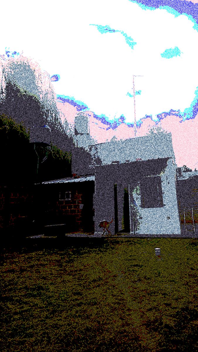 A white house under a pink-tinted sky above a strip of green grass.